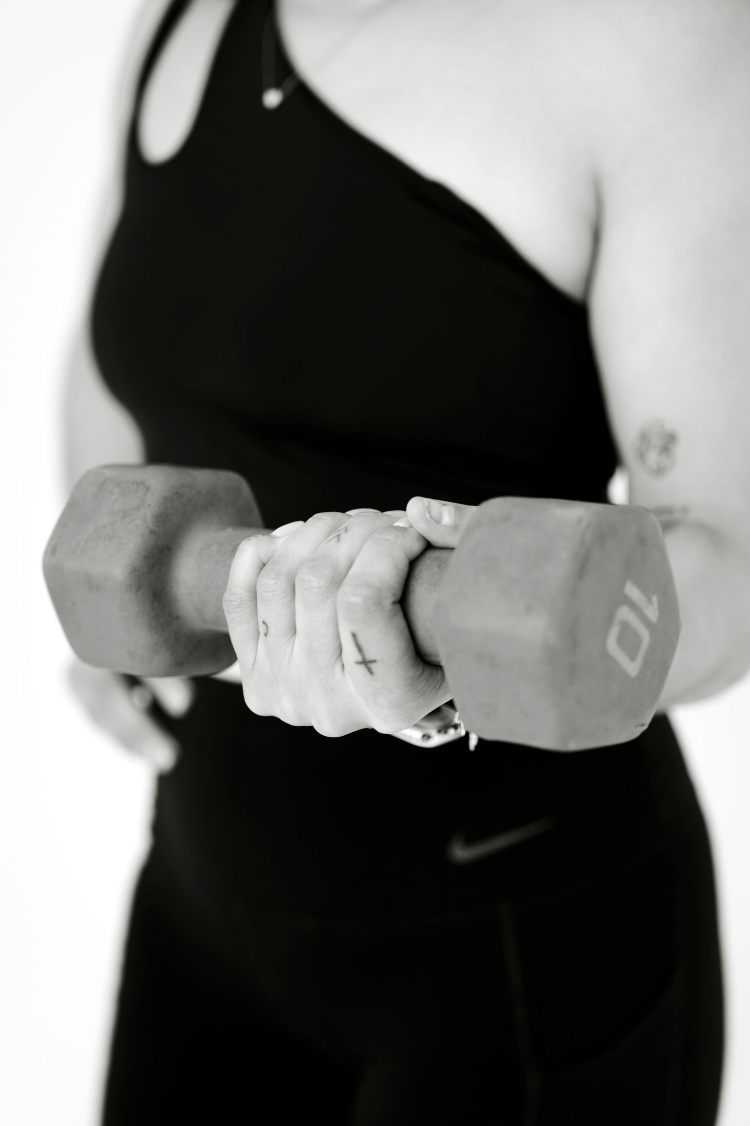 Woman in black athletic wear holding a 10lb dumbbell weight during a workout session.