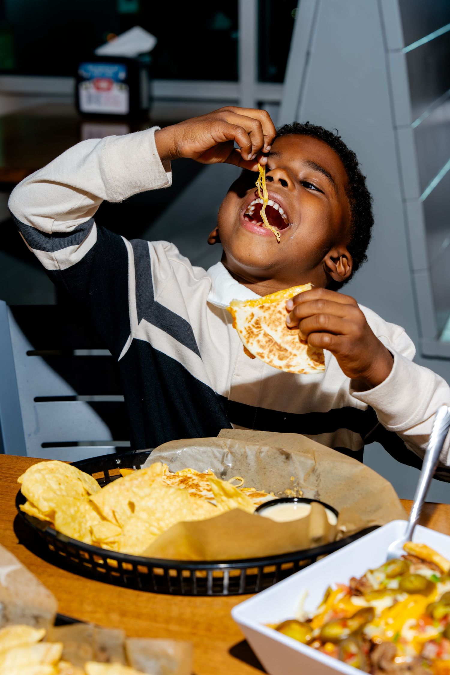Person enjoying cheesy nachos at casual dining restaurant.