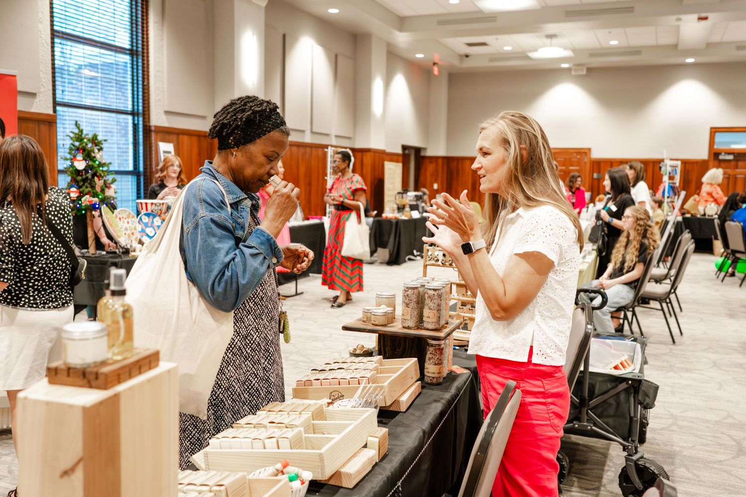 Attendees browse merchandise tables at an indoor community event.