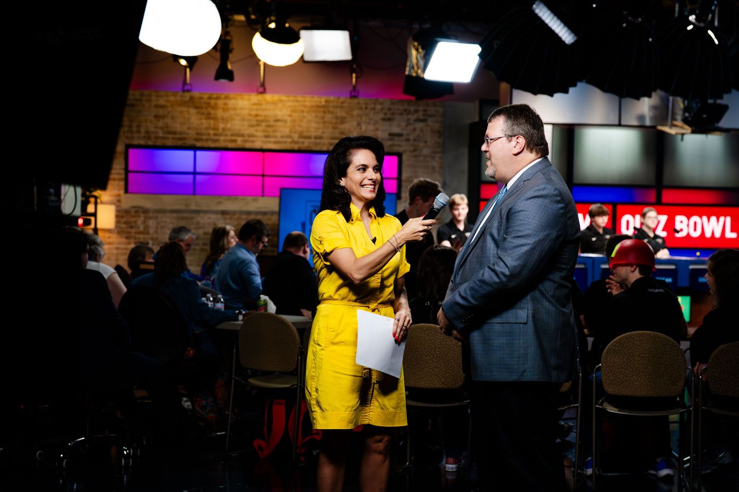 Indoor game show or trivia event setup with dramatic lighting and yellow uniforms.