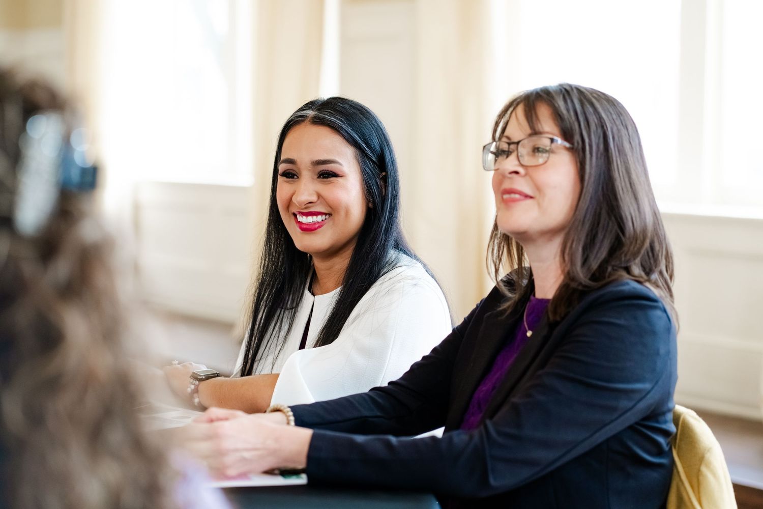 Professional conference attendees engaged in discussion at a bright, modern meeting venue.