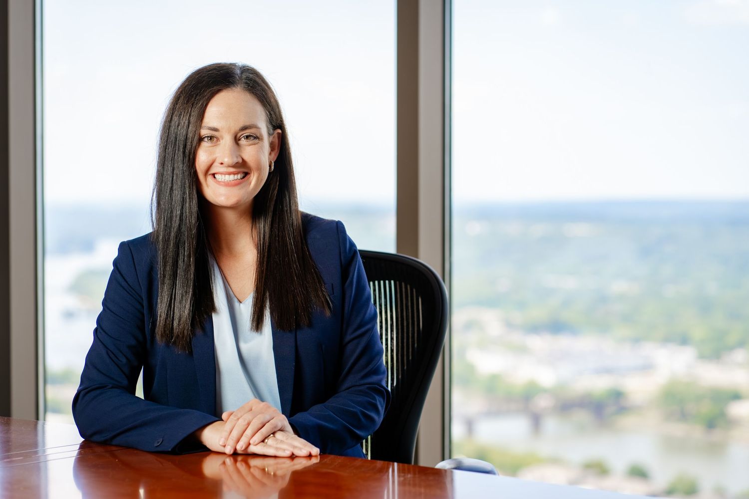 Professional executive seated at desk in modern office with city view.