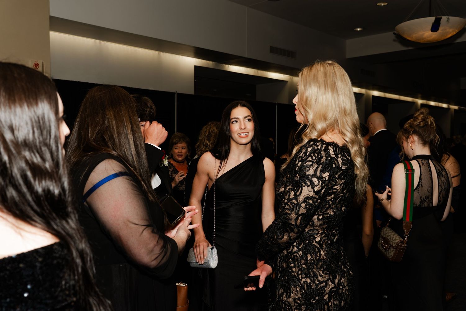 Guests mingling at an indoor social gathering with dramatic lighting effects.