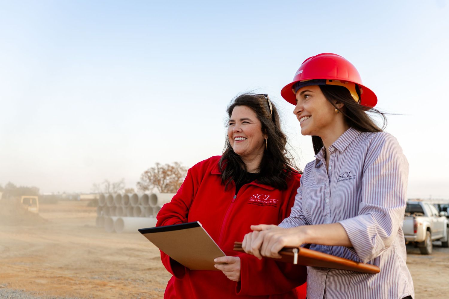 Construction team members review building plans and discuss project details at a construction site.