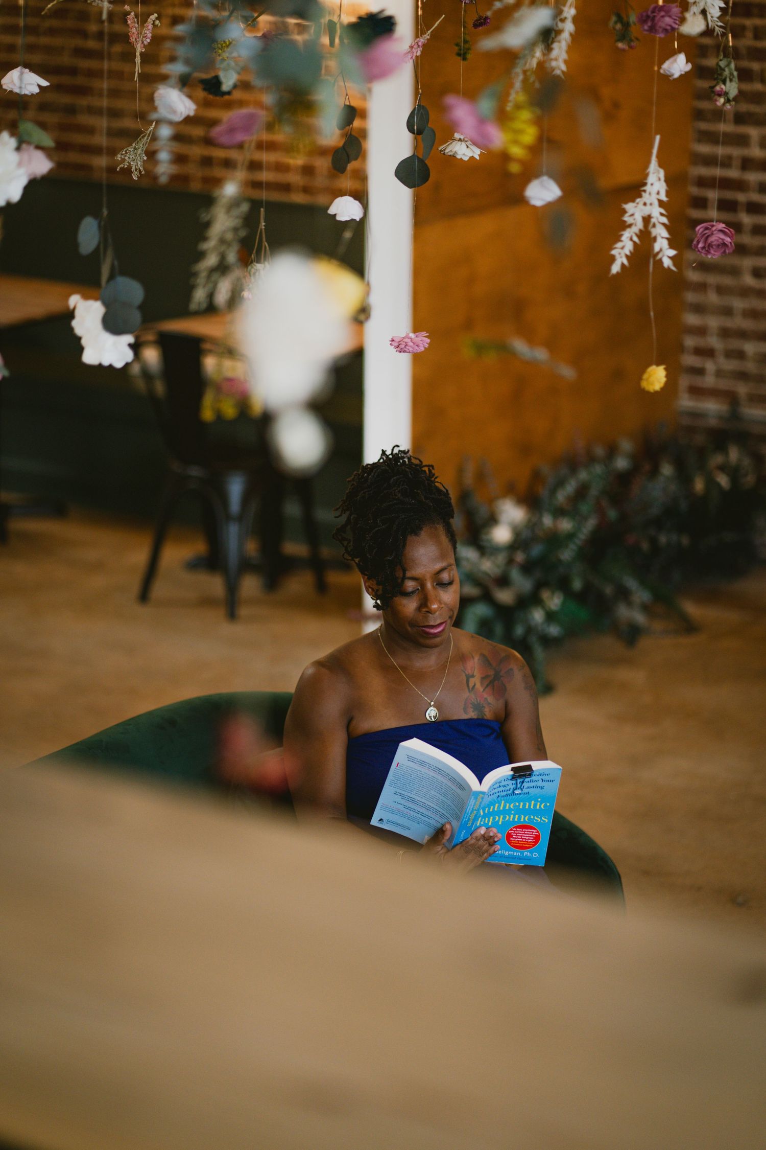 Person reading book in cozy cafe setting with decorative lights overhead.