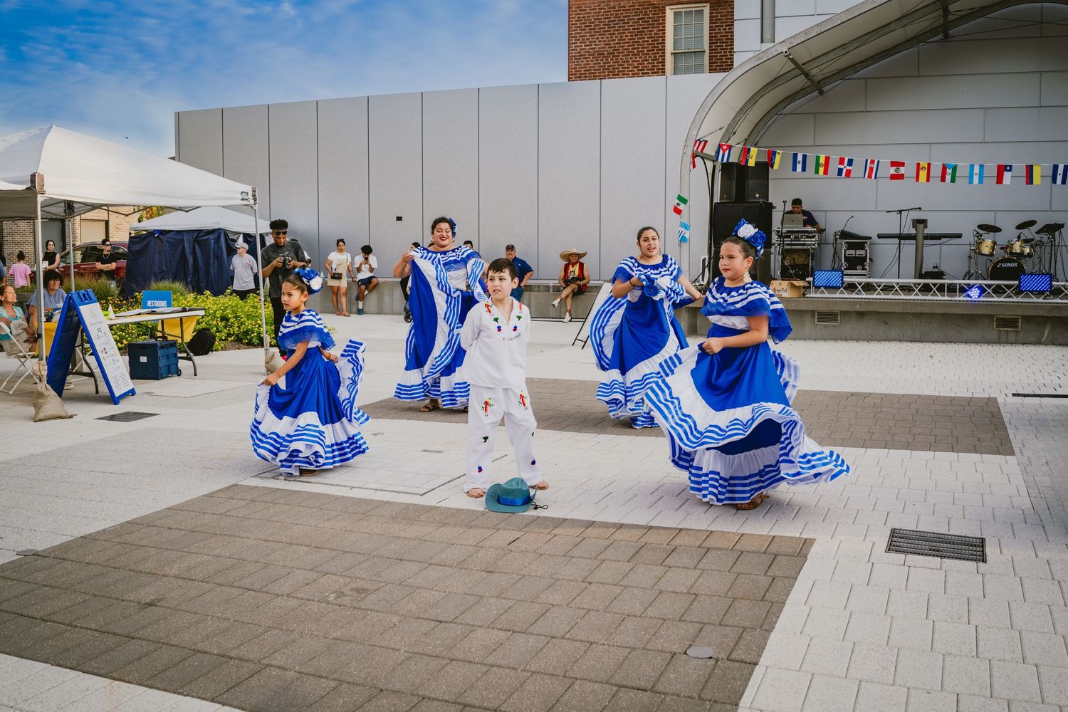 Traditional dancers in blue and white costumes perform at an outdoor festival.