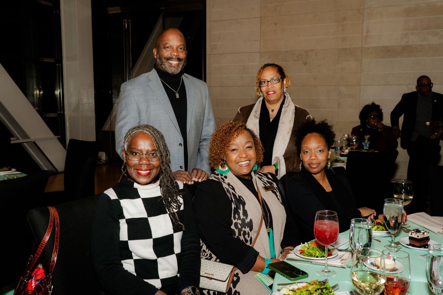Five people gather around a table at an elegant dinner event.