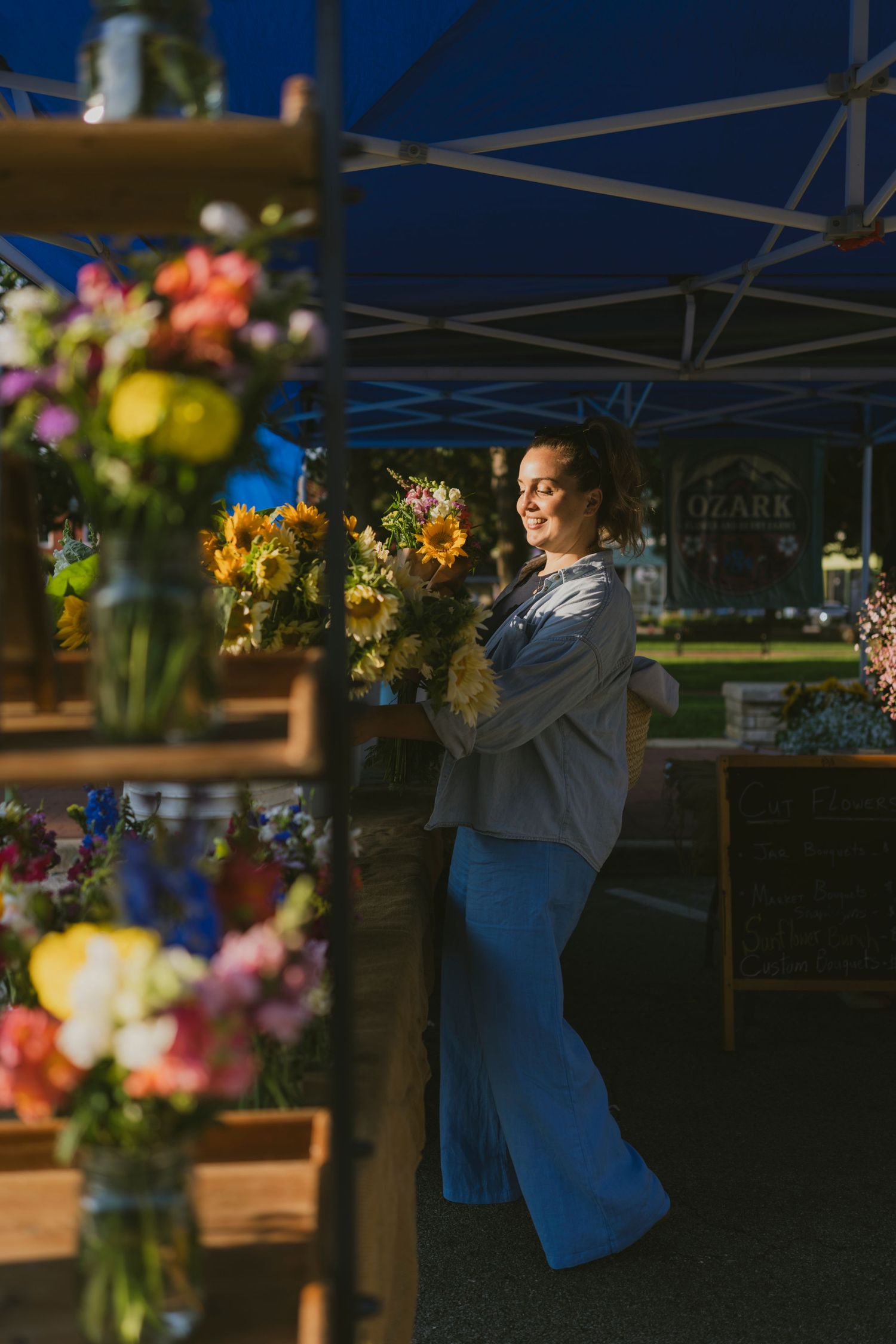 Woman smiling among colorful flower bouquets at an outdoor market stall at dusk.