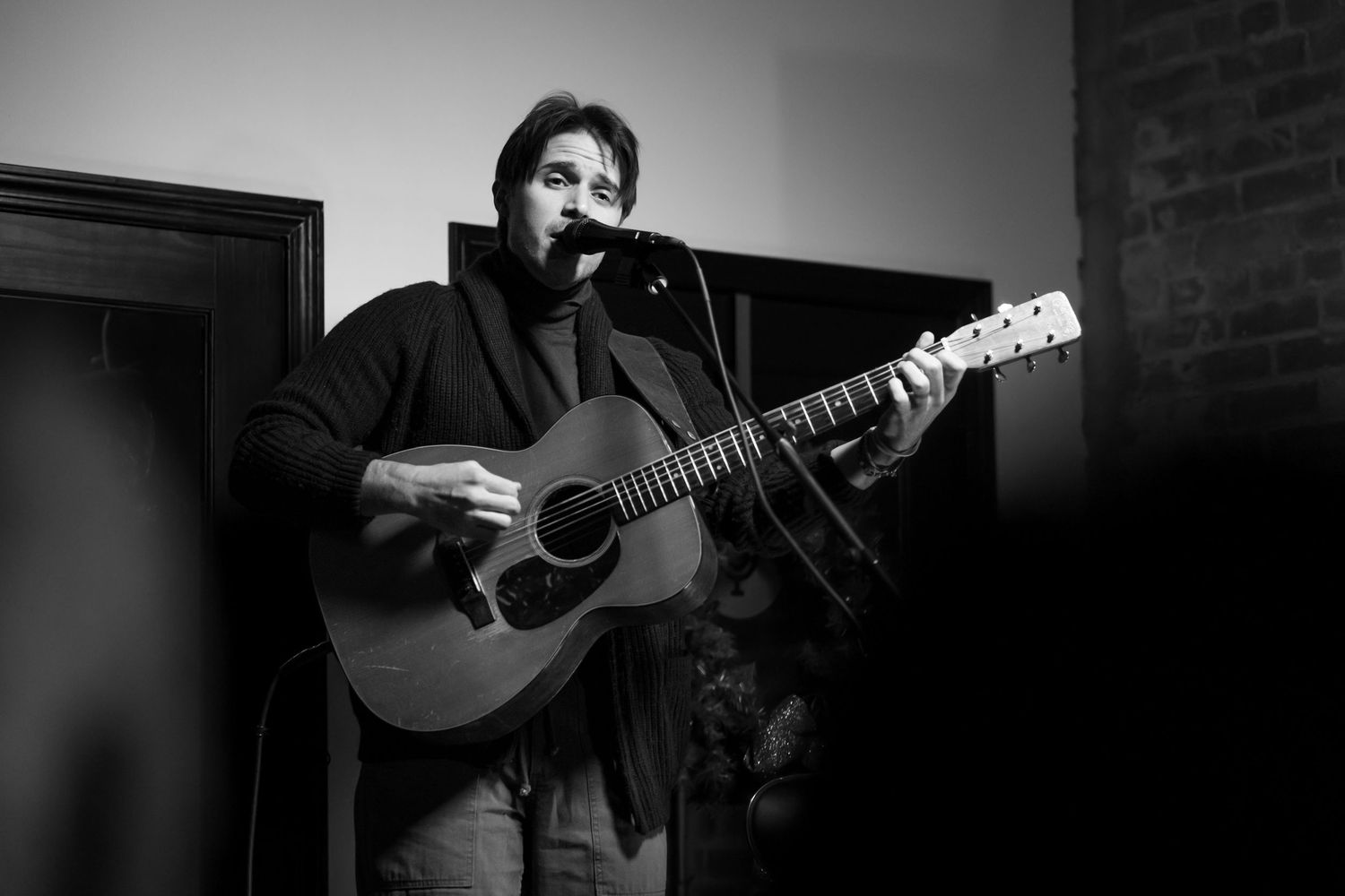 Musician playing acoustic guitar in dark moody lighting.