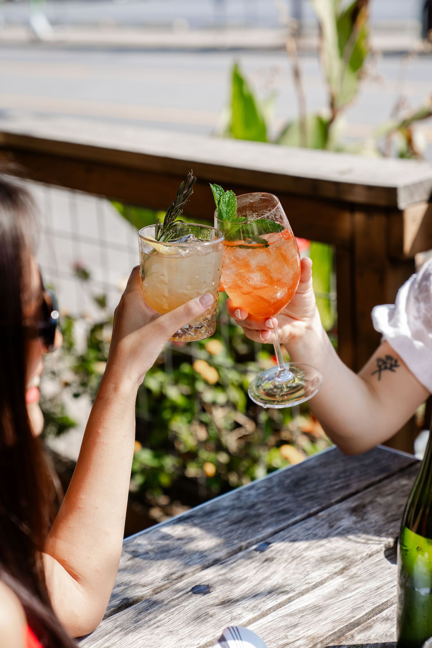 Two cocktail glasses clinking in a toast on an outdoor patio.