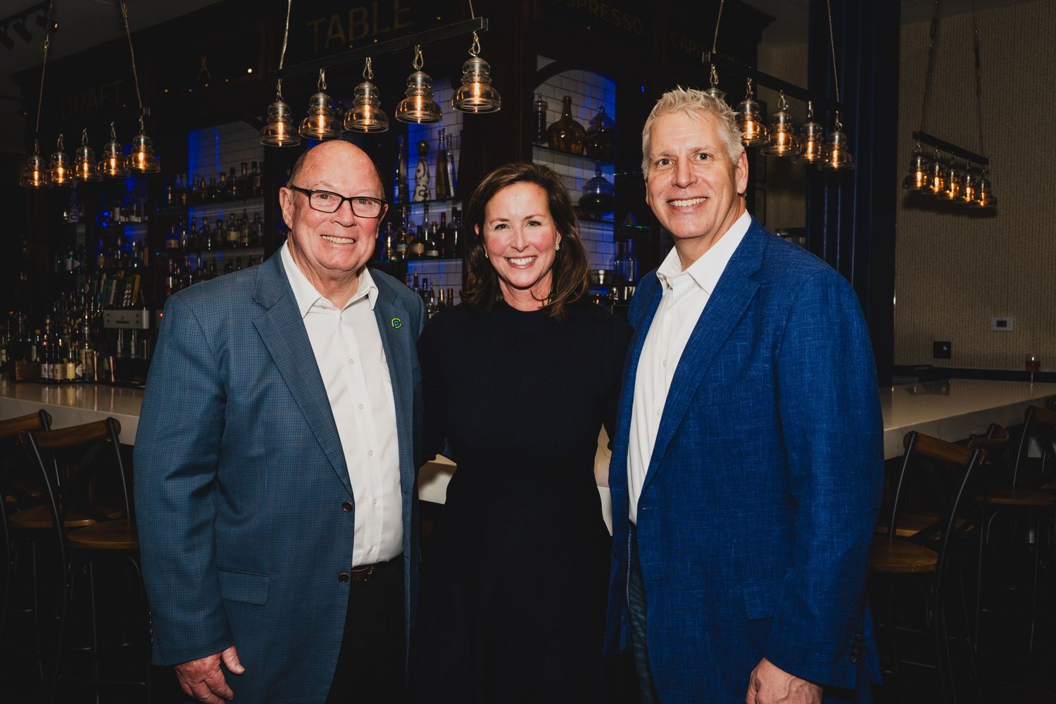 Professional networking event with attendees mingling in formal attire under ambient lighting.