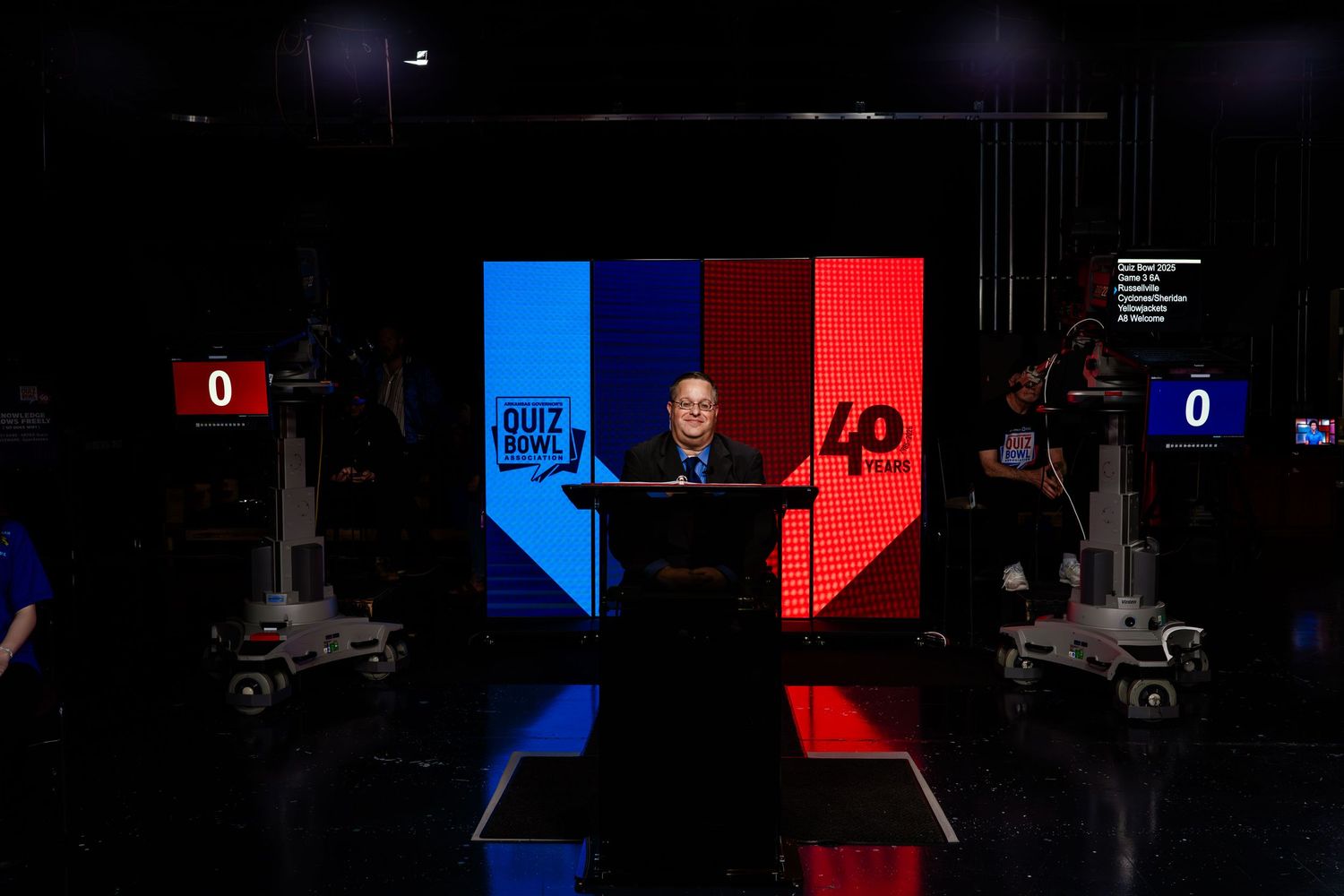 Game show studio setup with dramatic blue and red lighting and digital scoreboard displays.