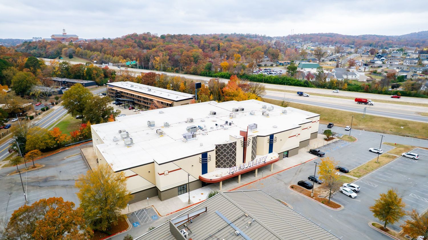 Commercial building with white exterior and parking lot during autumn season.