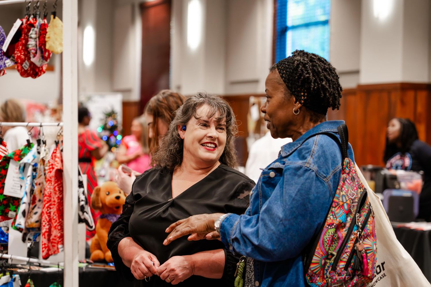Attendees browse vendor tables and displays at a busy indoor marketplace event.