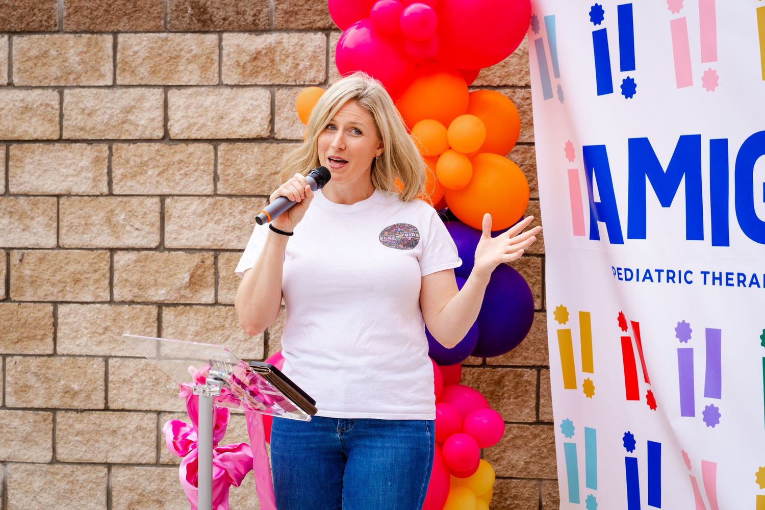 Celebration setup with pink and orange balloons against brick wall with Amigos branded banners.