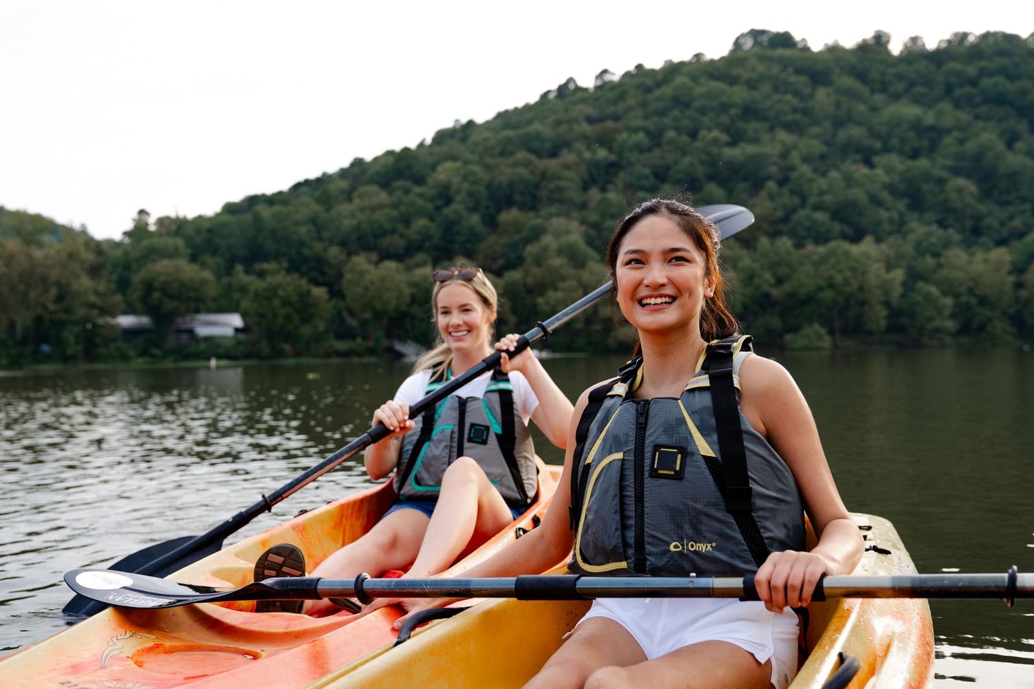 Group kayaking adventure on a scenic lake surrounded by forested hills.