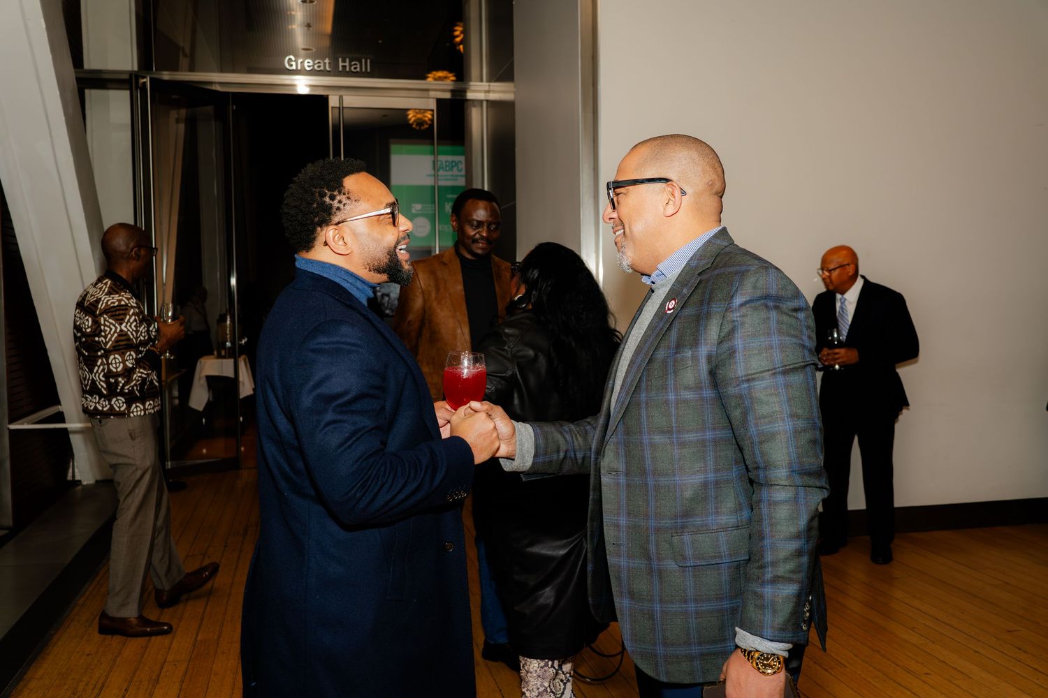 Two men in suits having an animated conversation at an indoor event.