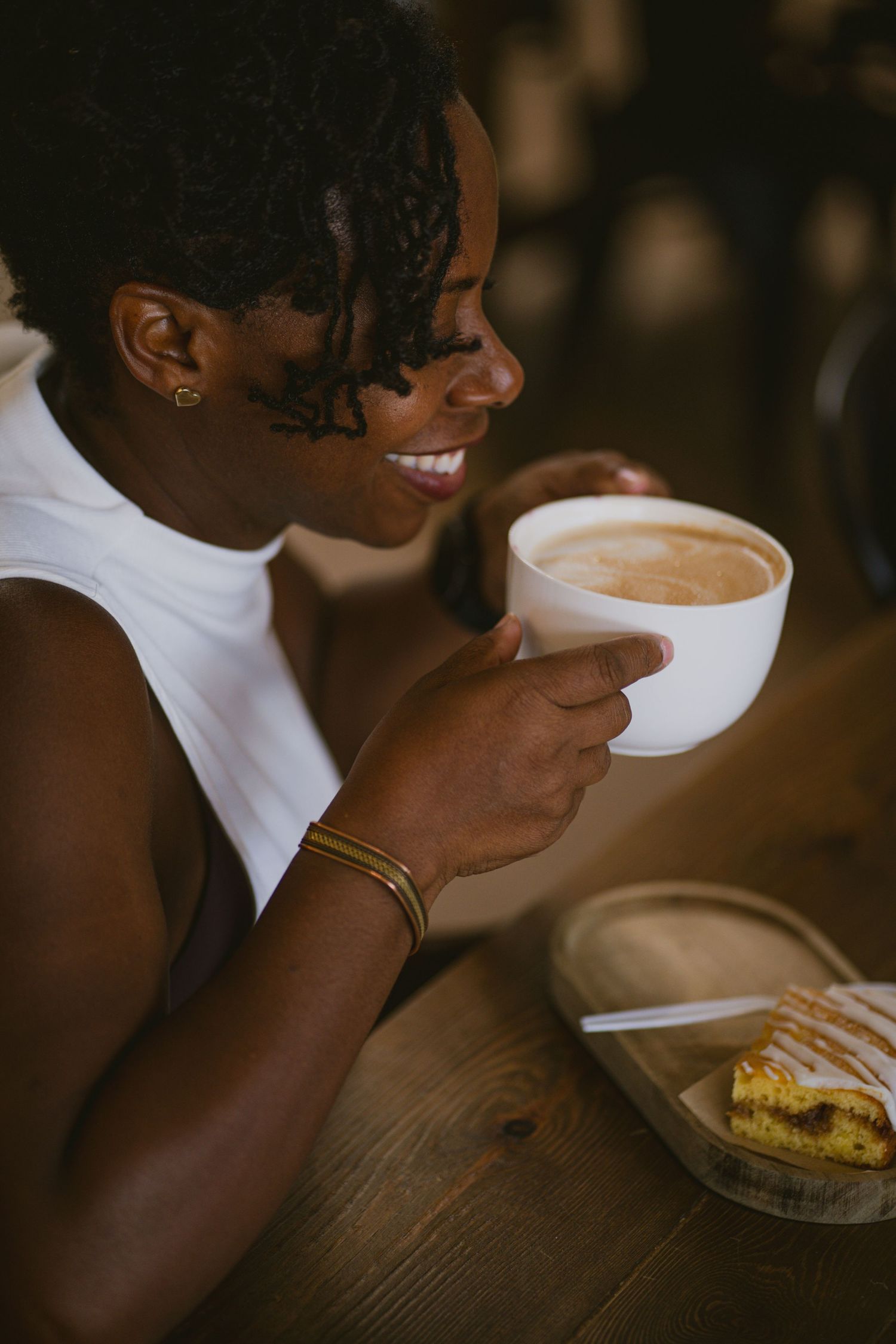Coffee drinker savoring a warm beverage at rustic wooden table.