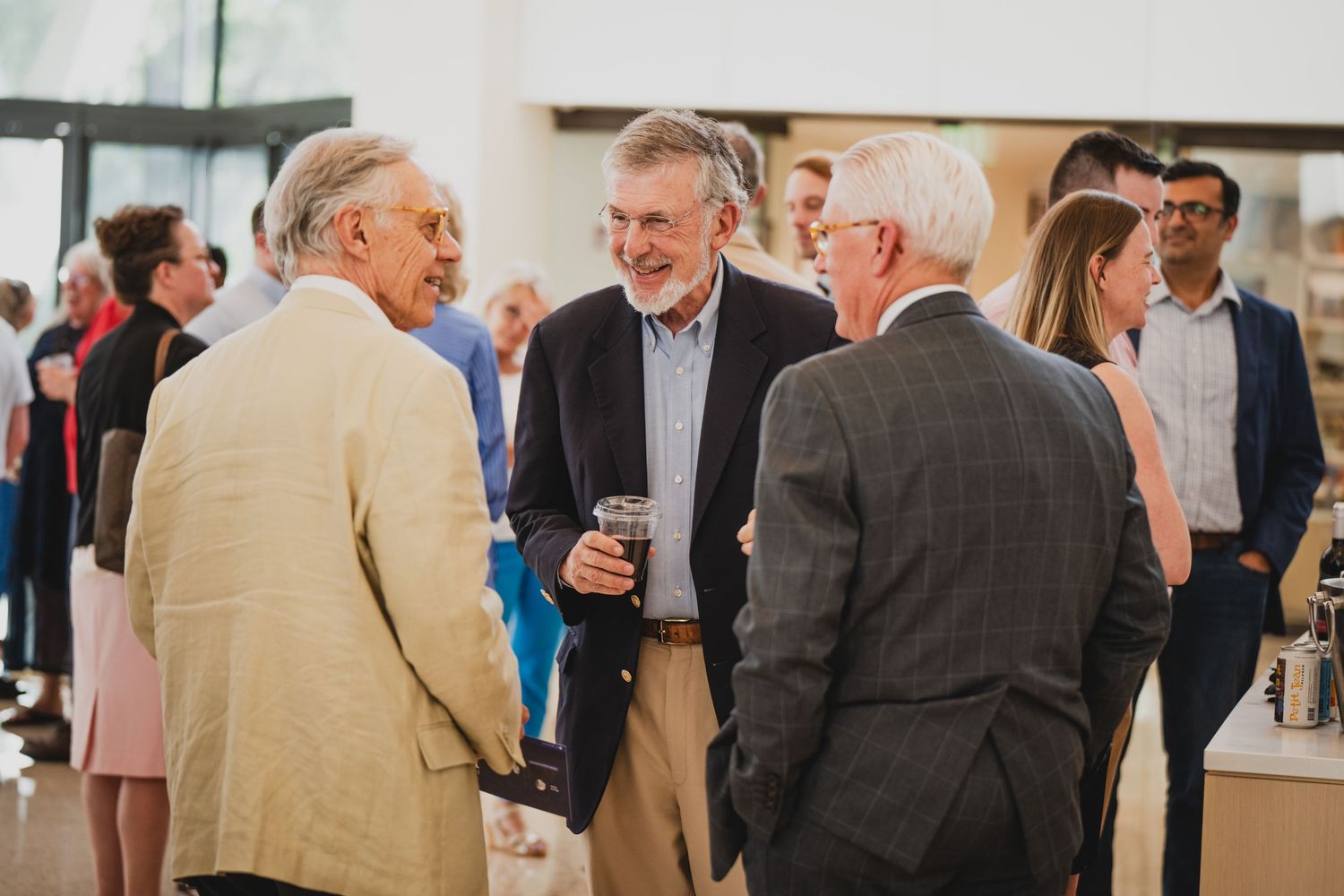 A group of people mingling and socializing at a professional networking event in a bright indoor space.