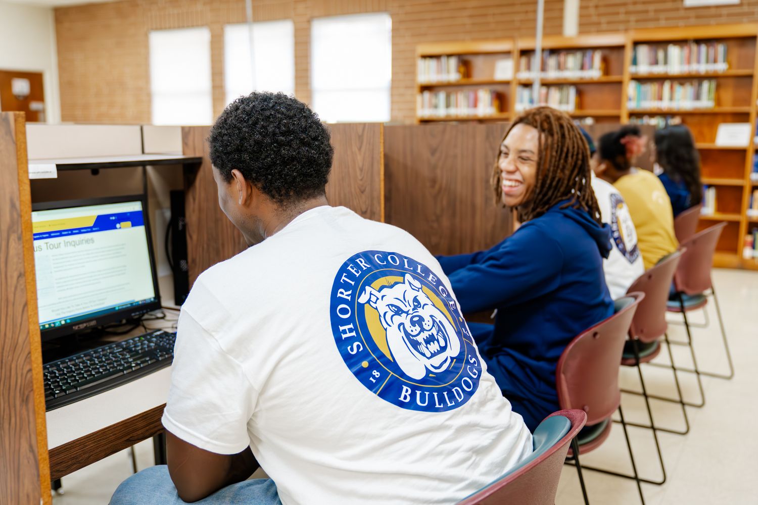 Students working at computer stations in a modern library setting.