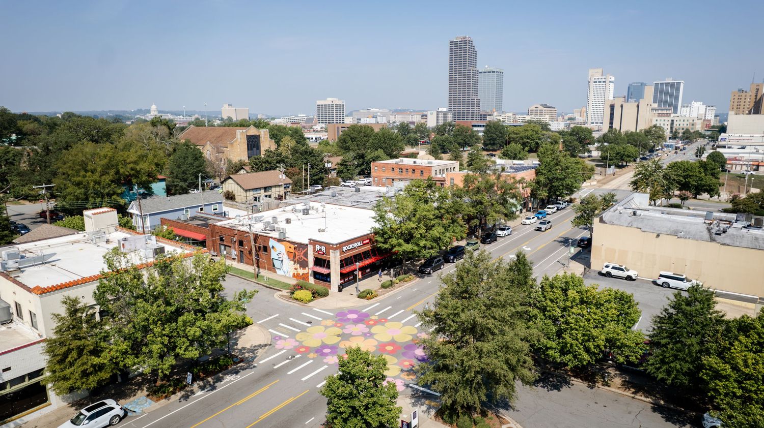 Aerial view of urban cityscape showing buildings and tree-lined streets.