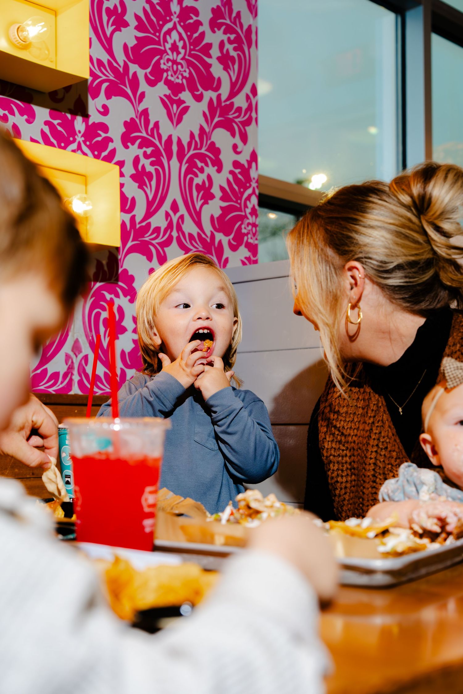Restaurant interior with pink damask wallpaper and diners enjoying a meal.