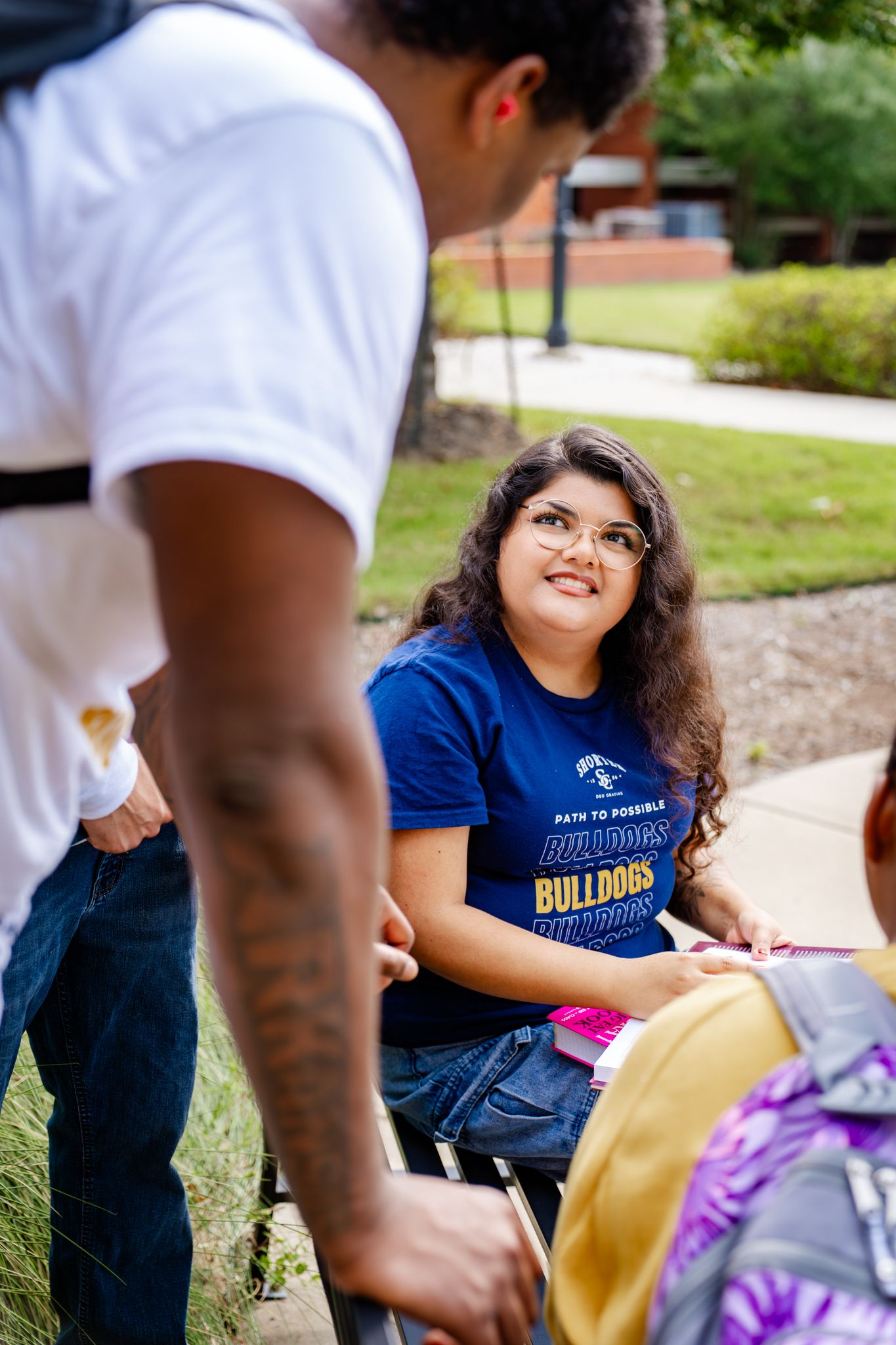 Students gathered outdoors on campus wearing university branded clothing.