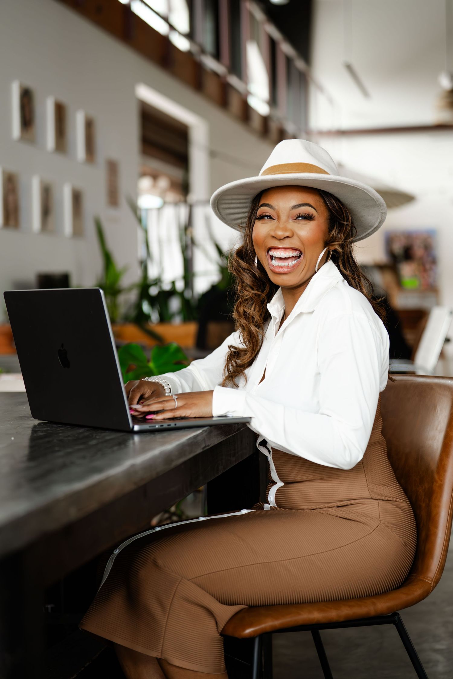 A professional working on a laptop in a modern office space wearing a white hat.