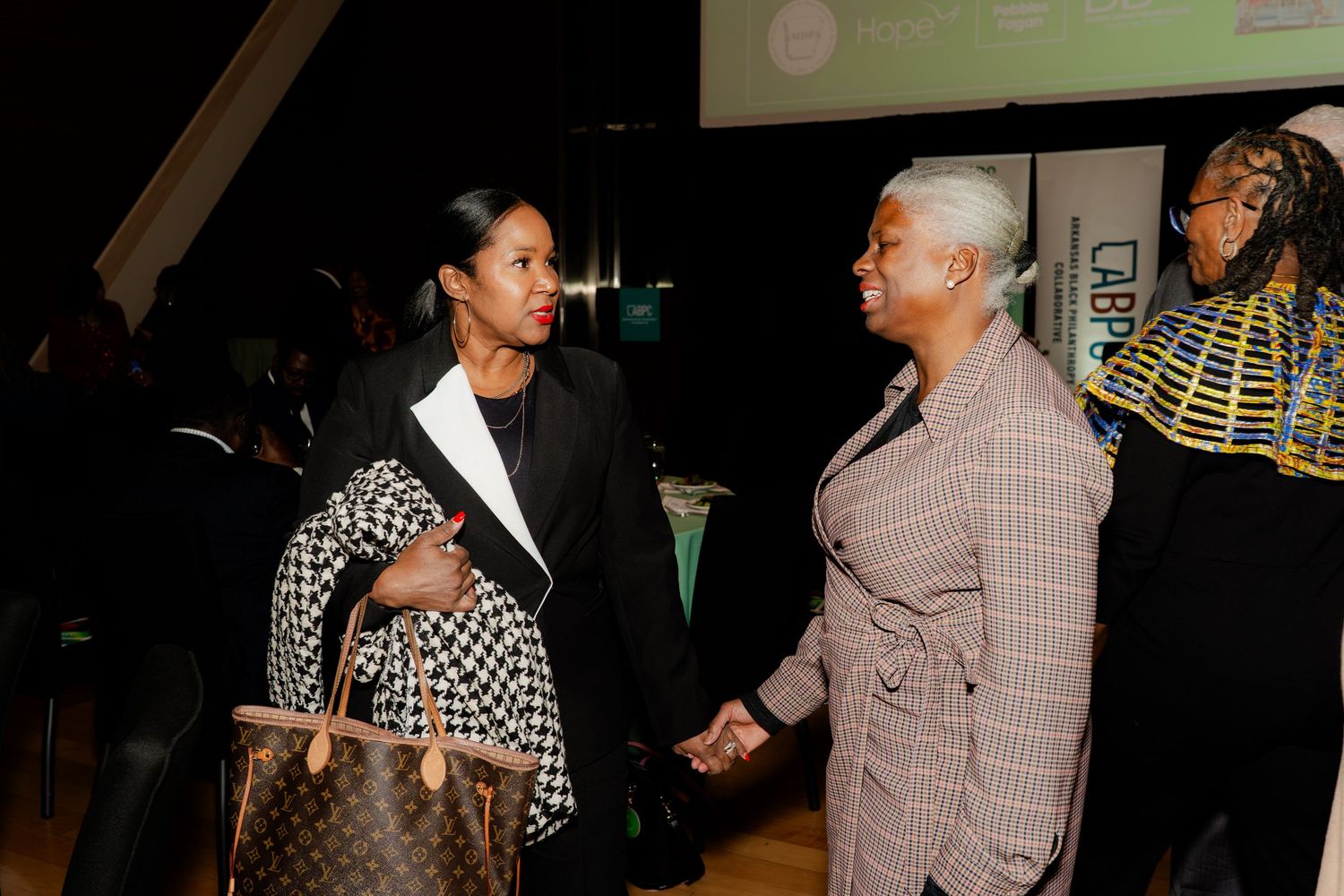 Three attendees having an animated conversation at an evening social function.