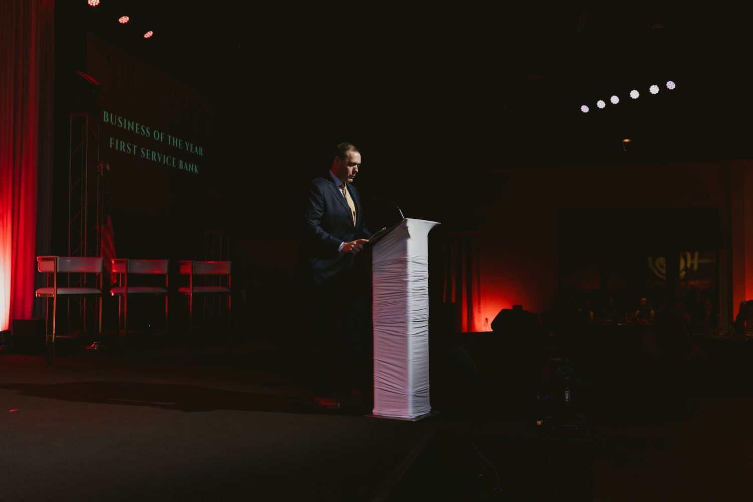 Dark auditorium with red stage lighting and dramatic shadows.
