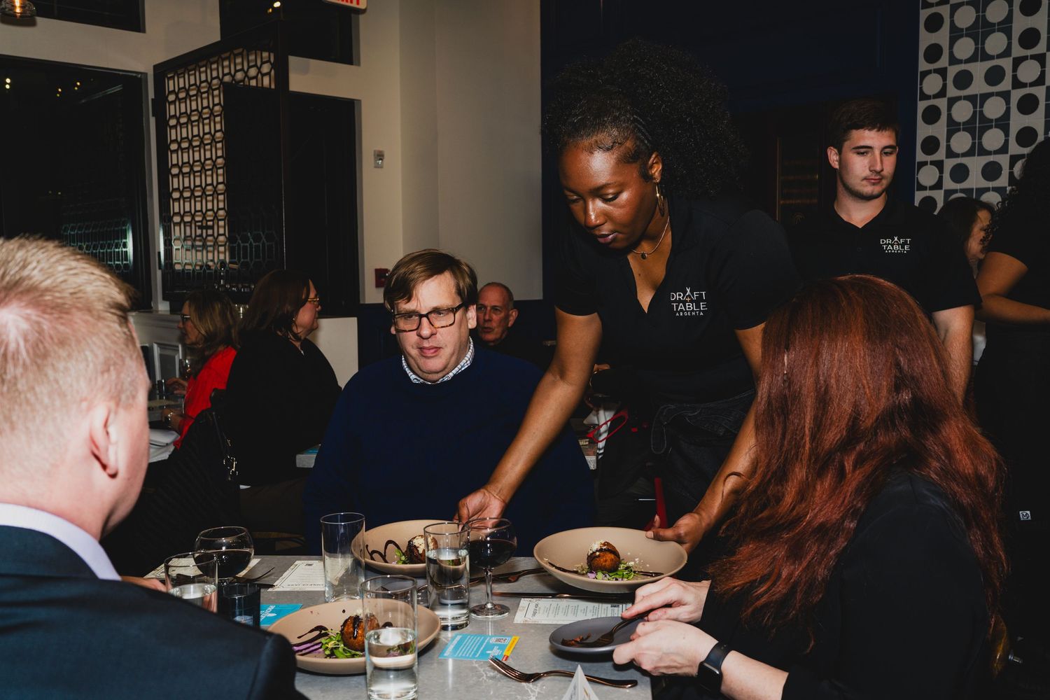 Diners enjoying a meal in a dimly lit restaurant setting.