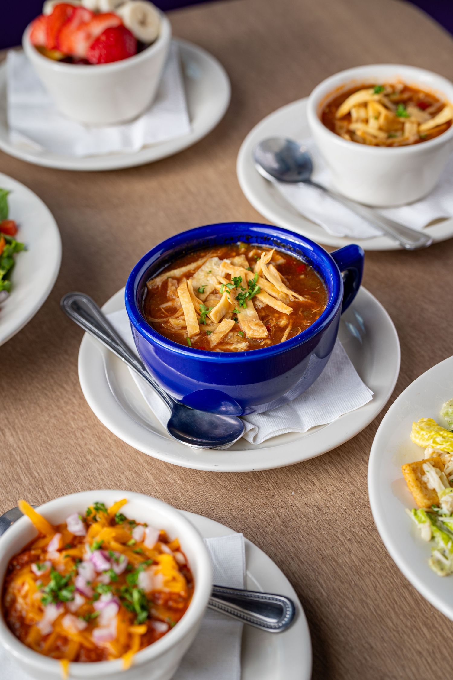 Various bowls of hot soup and side dishes arranged on a restaurant table.