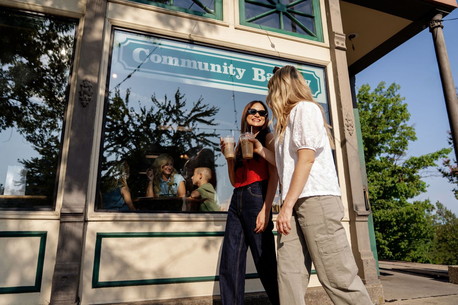 Two people chatting outside a community building on a sunny day.