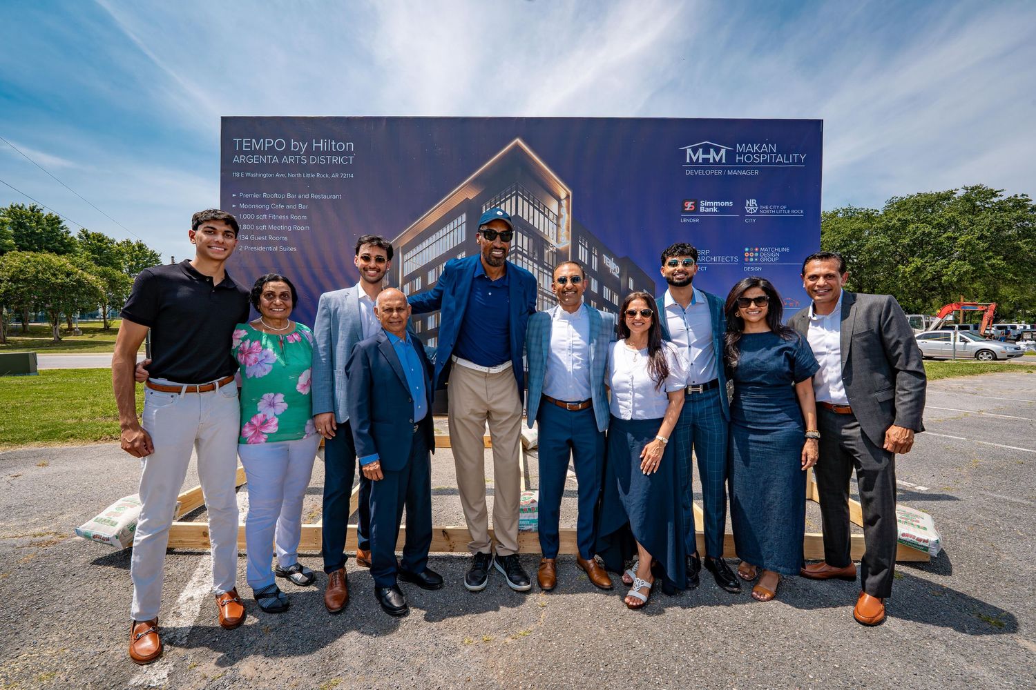 Group photo of people standing together in front of a project rendering sign outdoors.