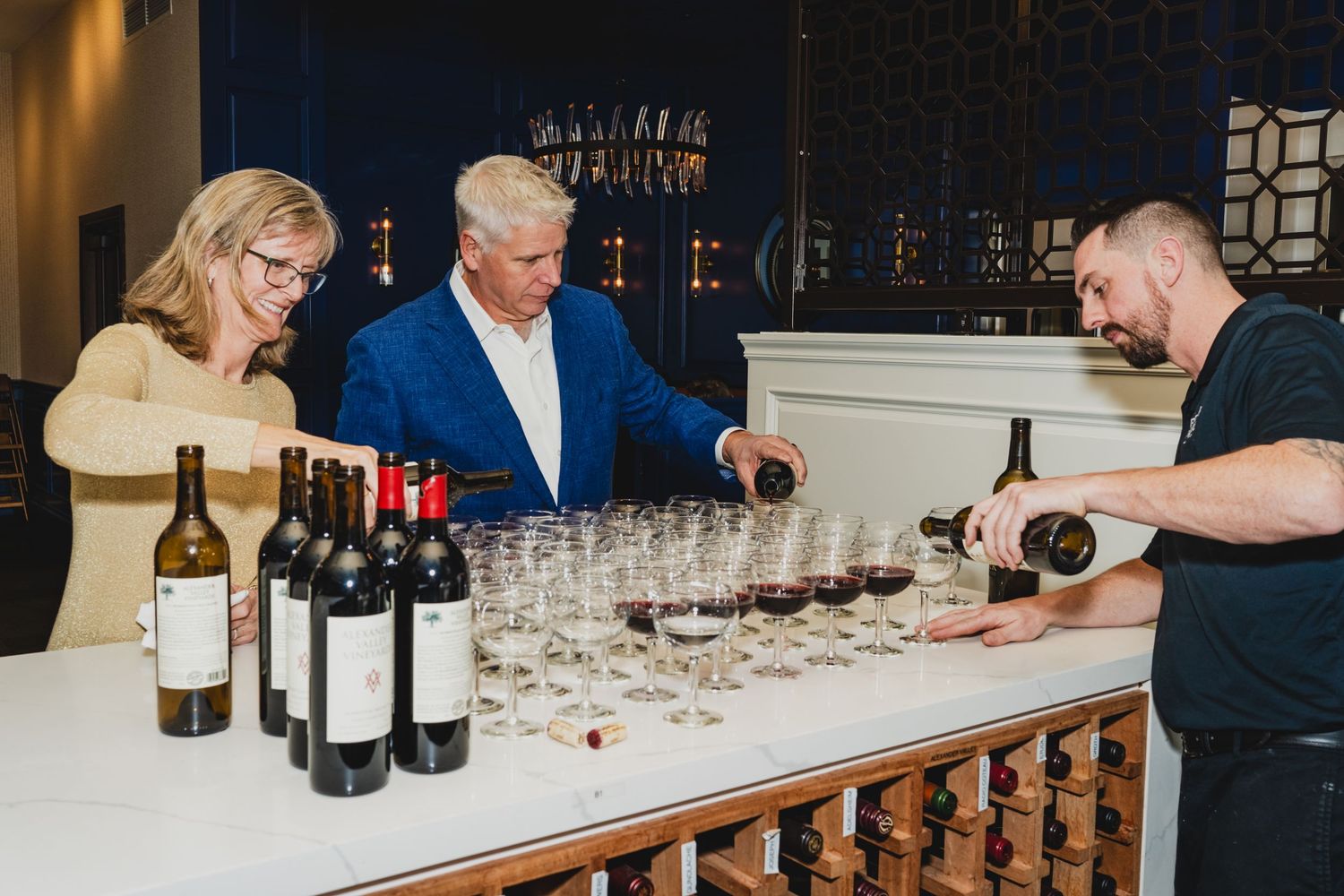 Wine tasting setup with multiple glasses and bottles arranged on a long white counter.