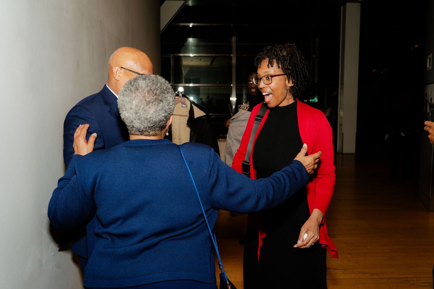 Three people engaged in animated conversation at an indoor event.