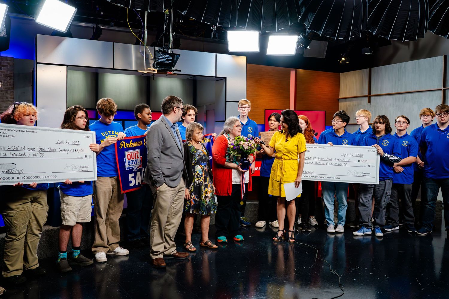 Large group presentation in a TV studio with oversized checks being displayed.
