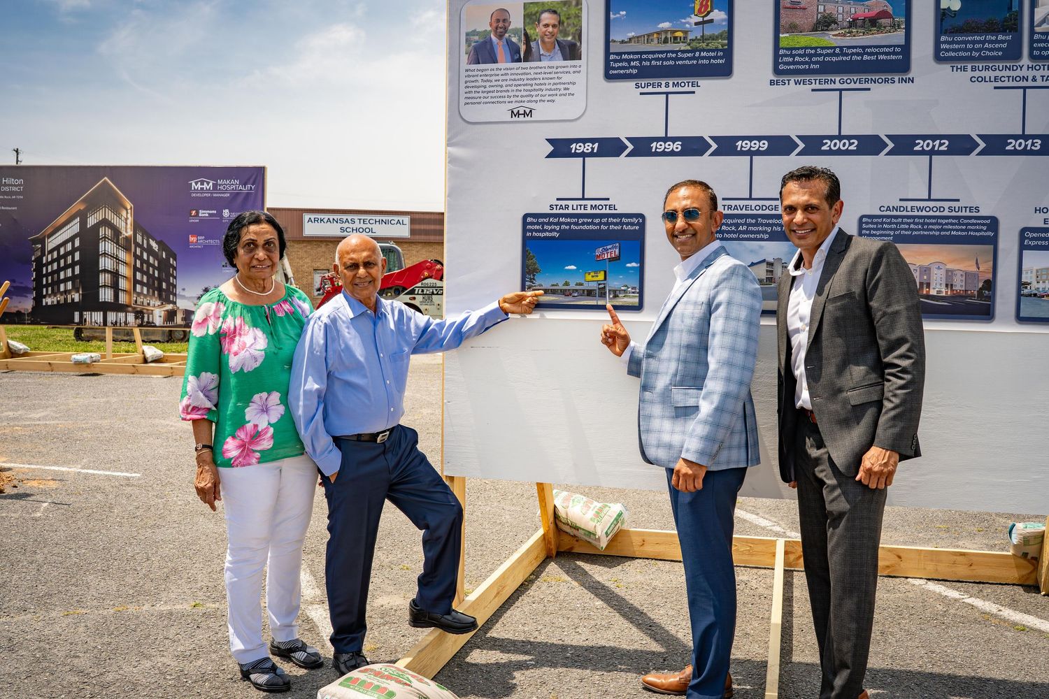 People standing in front of wall display showing architectural renderings and project plans.
