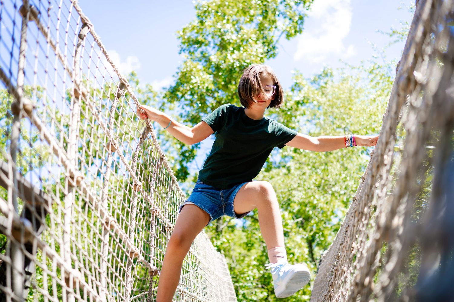 Dynamic sequence of a dancer leaping joyfully against a bright outdoor backdrop with trees and greenery.