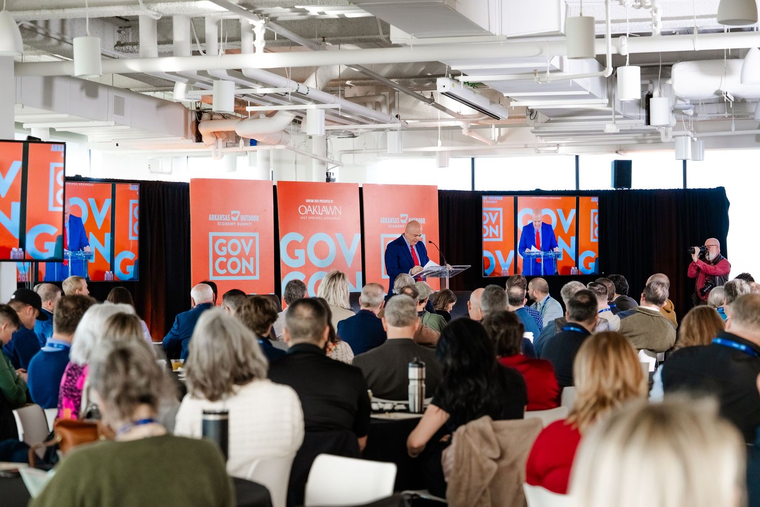 A business conference room filled with attendees listening to a presentation.