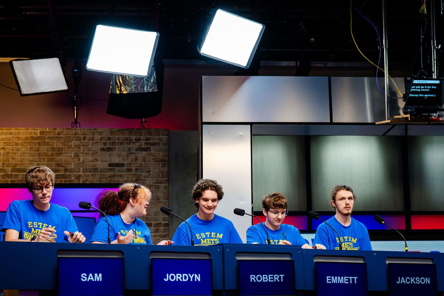 Row of illuminated game show style podiums with name displays.