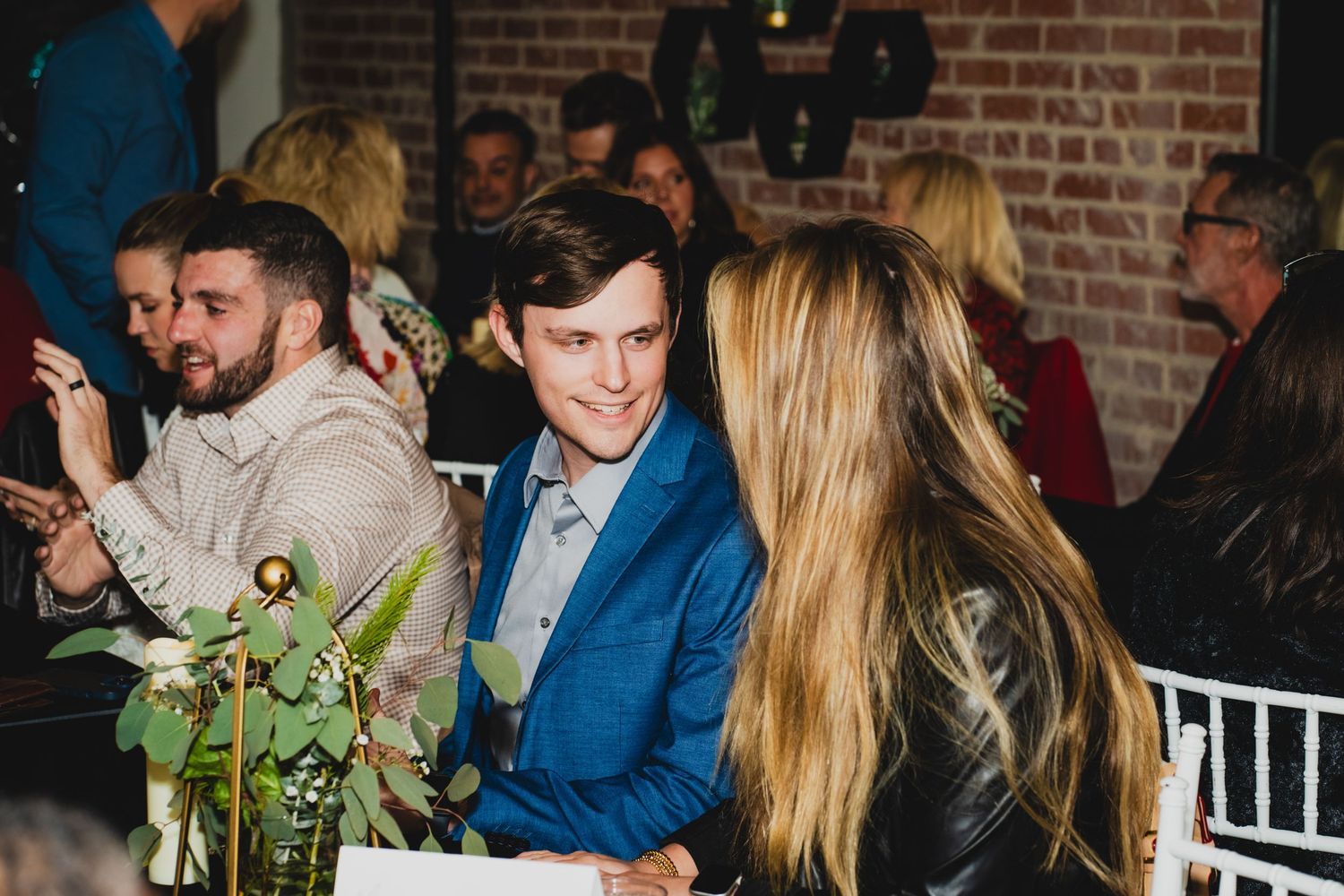 Holiday celebration with guests mingling near decorated Christmas tree and brick walls.