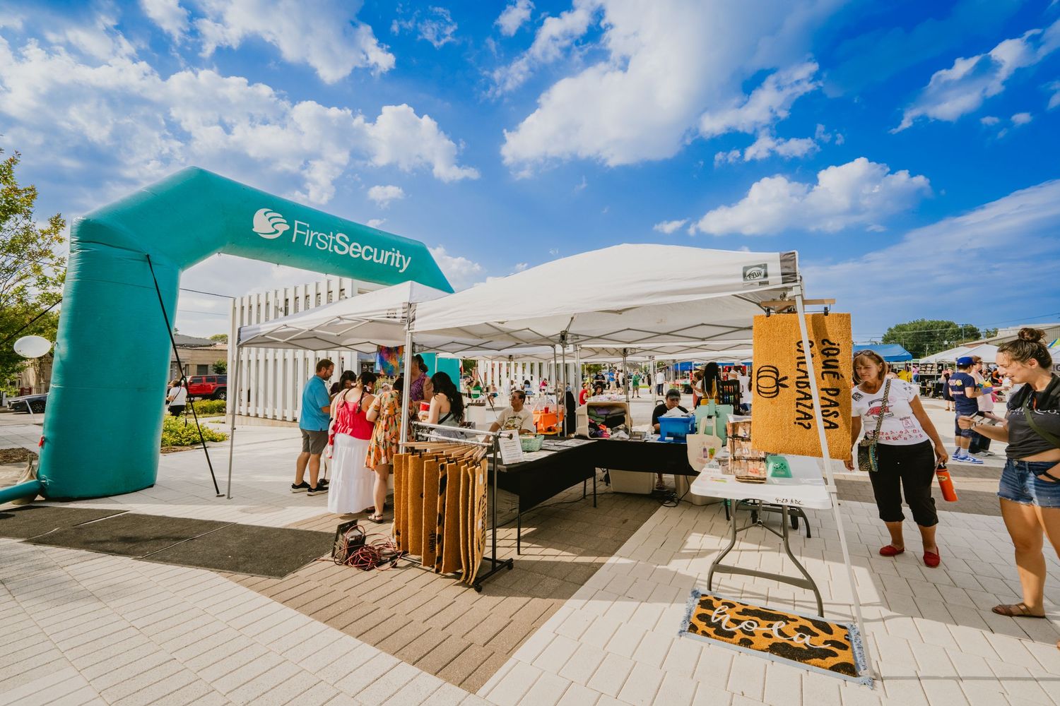 Event setup with white tents and vendor booths under bright blue summer sky.
