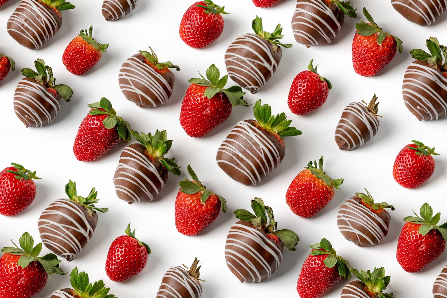 Fresh strawberries and chocolate-dipped truffles arranged in alternating rows on a white background.