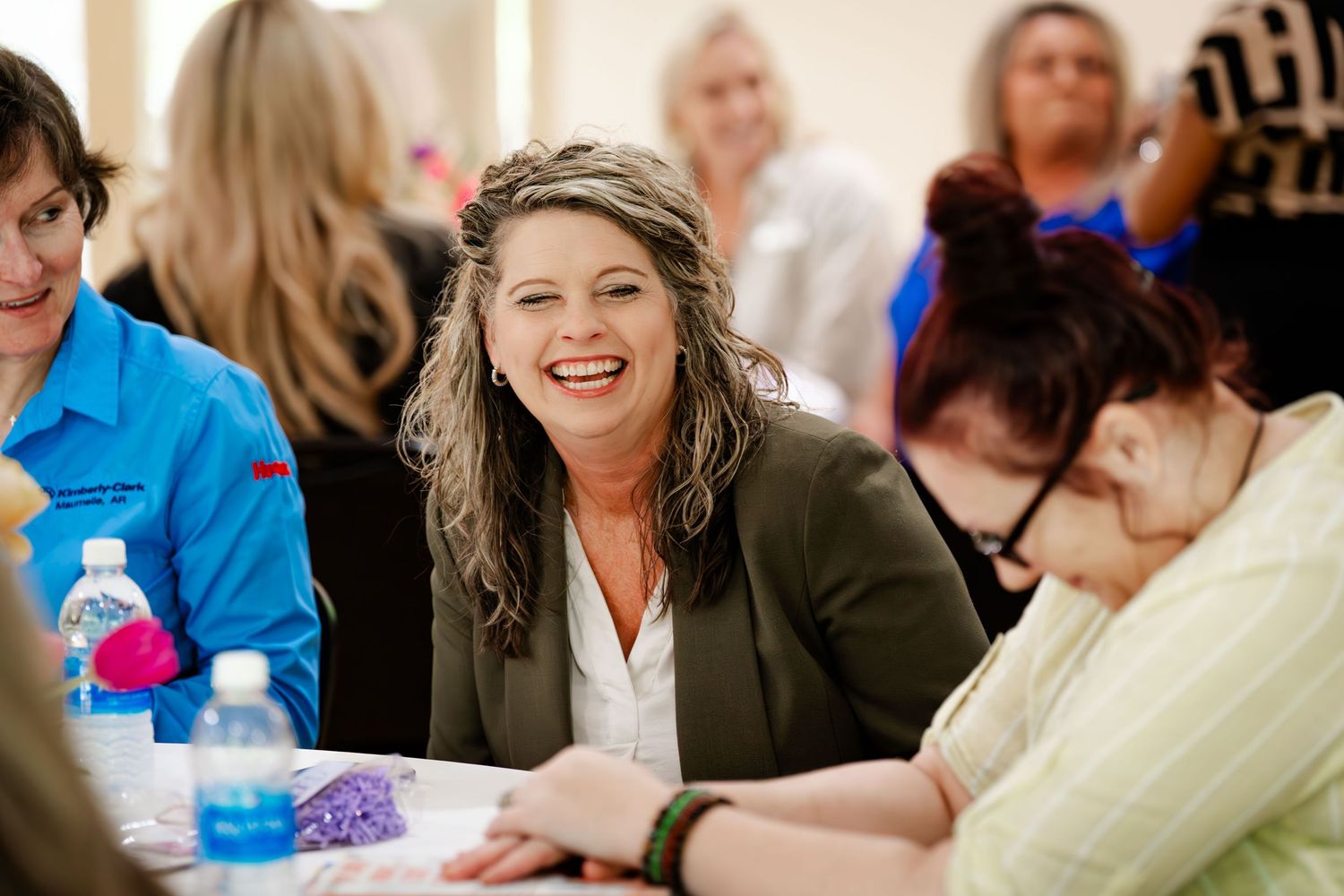 Casual business meeting with participants seated around tables engaged in discussion.