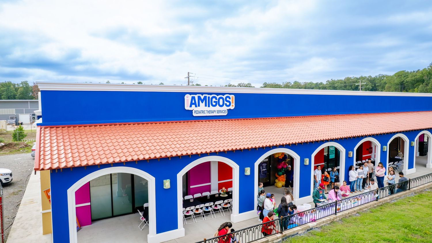 Colorful exterior of Amigos pediatric therapy center with blue and orange walls and arched doorways.