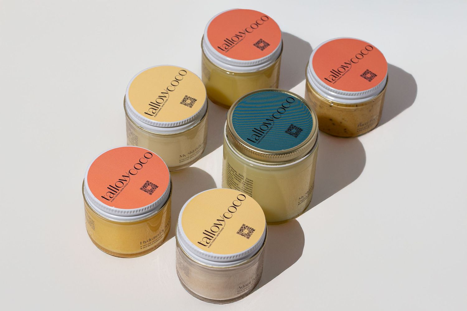 Collection of colorful skincare product jars arranged in a row on white surface.