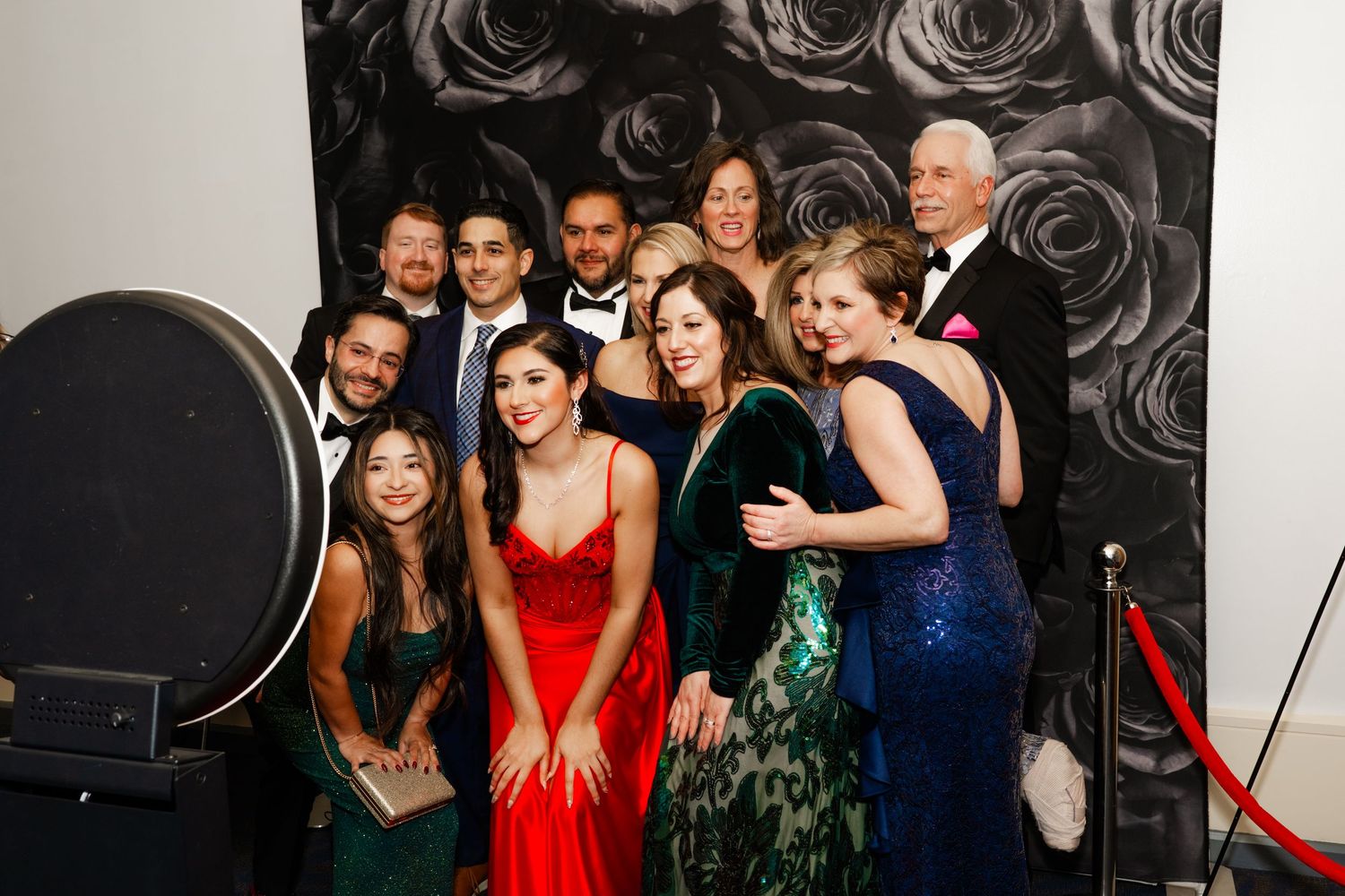 Black and white rose pattern backdrop at formal gala with guests posing for photos.