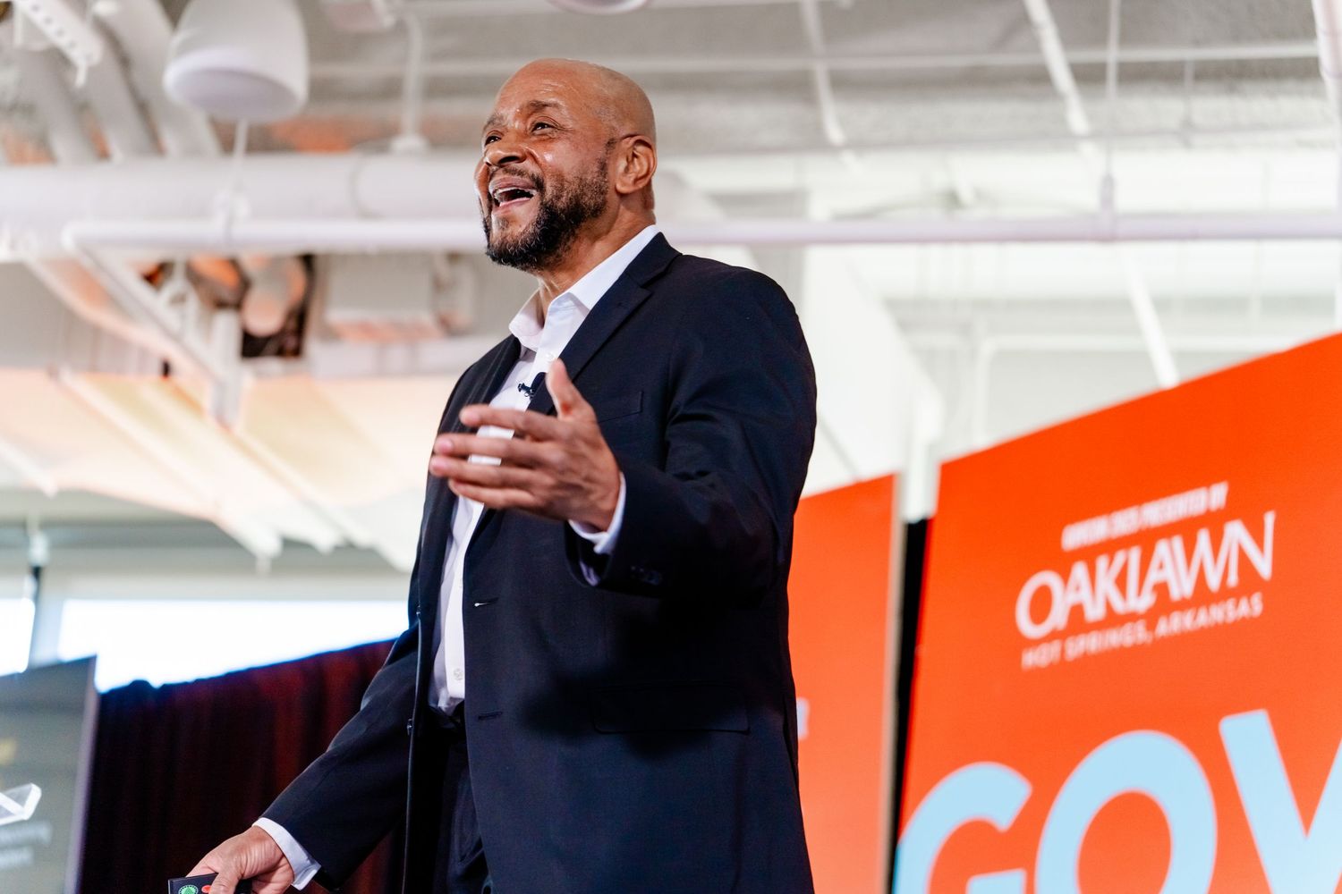 Conference stage setup with bright orange branding and white industrial ceiling.