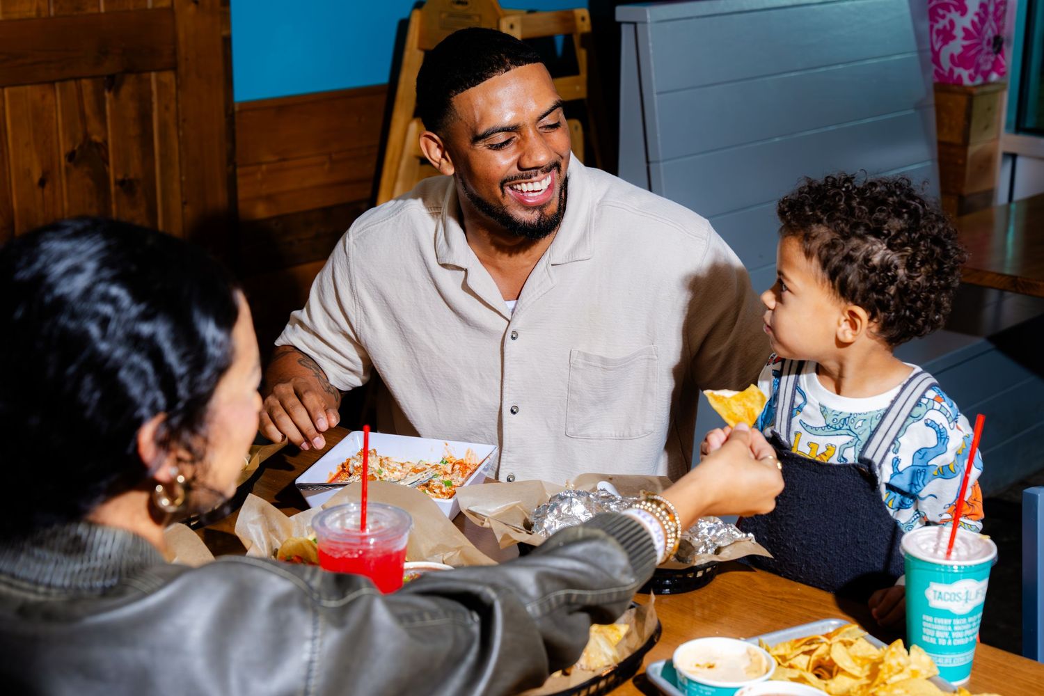 A family enjoying a casual meal together at a restaurant table with drinks and food.